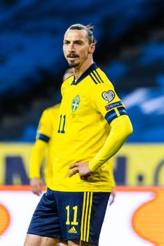 a soccer player is standing on the field with his hands in his pockets and looking down