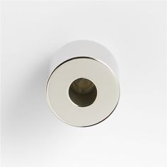 a white toilet paper holder on a white wall with a black and brown object in the middle