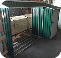 a green metal shed sitting inside of a garage