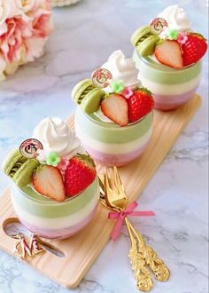 three desserts with strawberries and whipped cream in small bowls on a wooden tray