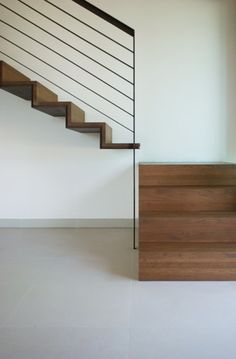 a wooden stair case next to a white wall