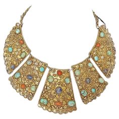 Silver gold gilt Persian bib necklace with turquoise Middle Eastern Antiques A Highly detailed gold gilt metal Persian bib necklace influenced by the ancient style with turquoise and coral stones. Round and oval stones in filigree settings. separate plaques with jump rings creating a beautiful bib design. Measures 7" Wide ; weighs approx. 130 grams. Gold Turquoise Necklace Costume Jewelry For Gift, Gold Turquoise Costume Jewelry Necklace For Gift, Gold Jeweled Jewelry For Festivals, Festival Jeweled Gold Jewelry, Bohemian Jeweled Gold Necklace, Gold Jeweled Festival Jewelry, Bohemian Gold Turquoise Necklace With Natural Stones, Bohemian Antique Gold Filigree Jewelry, Handmade Vintage Gold Turquoise Necklace