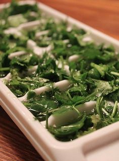 a tray filled with green vegetables on top of a wooden table