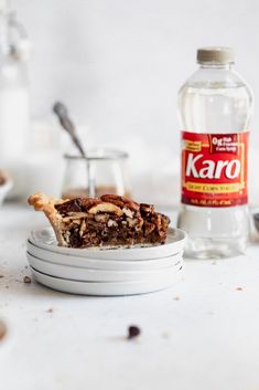 a piece of pie sitting on top of a white plate next to a bottle of karo