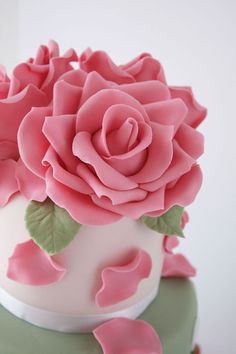 a close up of a cake with pink flowers on it's top and green icing