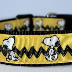 a yellow dog collar with black and white snoopy dogs on it's side