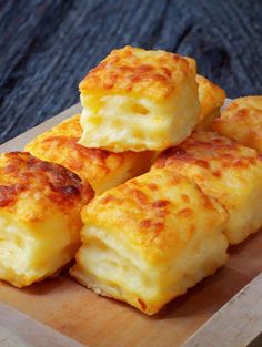 four cheesy biscuits sitting on top of a wooden cutting board