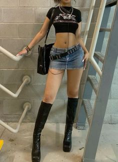 a woman in short shorts and black boots standing next to a stair case with her hand on her hip