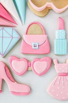 decorated cookies with pink, blue and white icing on top of a table next to cookie cutters