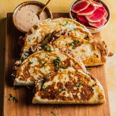 four quesadillas on a cutting board with dip