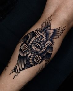 a black and white owl with an eye tattoo on it's arm