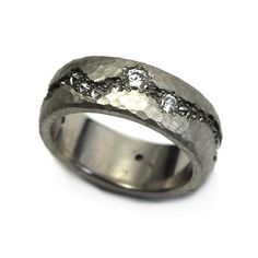 a wedding ring with three diamonds on it's side and in the middle, is made out of silver