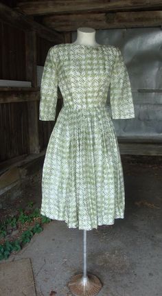 This is a silky green and white print full skirt dress from the late 1950's or early 1960's.  It features a wide neckline, below elbow length sleeves and full skirt pleated into the waist.  Opens down the back with a well working zipper.  In great shape.  Comes from a smoke free home.Measurements:  Bust:  35"   Waist:  25"   Hip: Full     Bodice Depth:  15.5"   Waist to Hem:  27"   Length:  43"Please ask me any questions you may have before buying as this is a final sale. Please know your measur Vintage Pleated Full Skirt Dresses, Vintage Green Dress With Full Skirt, Green Retro Dress With Full Skirt, Green Retro Full Skirt Dress, Green Knee-length Vintage Dress For Vintage Fashion, 1950s Style Green Lined Dress, 1950s Style Green Dresses For Daywear, 1950s Style Green Vintage Dress For Spring, 1950s Style Green Short Sleeve Dress