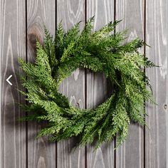 a green wreath sitting on top of a wooden table next to an arrow pointing in the opposite direction