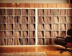 a chair in front of a bookcase full of records