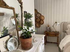 a bedroom with a bed, mirror and plants on the table in front of it