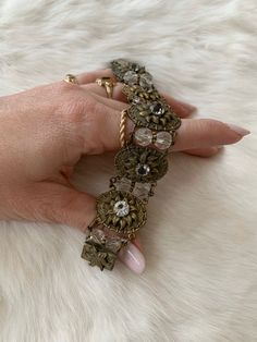 This Vintage 1930's Bead and Stamped Gold Tone Bracelet add romance and whimsy to any occasion. The metal is gold tone. The top of the metal is a flower shape, similar to a sunflower. The center of the flower is a zircon crystal adding pop and sparkle. In between the metal portions there are 2 crystal tone beads. The clasp of the bracelet even has a leaf embellishment. This bracelet is light-weight, flexible, and shows little signs of age.Length: 7.5 InchesWidth: 1 inchUnless otherwise stated al Elegant Antique Gold Metal Bracelets, Elegant Antique Gold Brass Bracelet, Elegant Antique Gold Metal Bracelet, Elegant Brass Bracelets With Antique Finish, Jeweled Gold Brass Bracelet, Antique Gold Adjustable Jewelry For Vintage Collection, Gold Vintage Charm Bracelets For Wedding, Gold Jeweled Brass Bracelet, Antique Jeweled Metal Jewelry