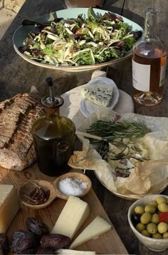 an assortment of cheeses, olives and bread on a picnic table