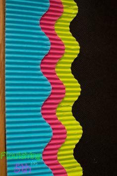 multicolored wavy design on the side of a wall with wood flooring and black background