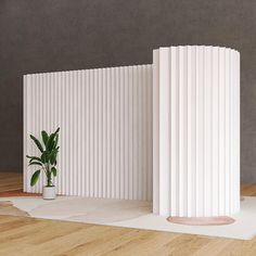 two tall white columns sitting on top of a wooden floor next to a potted plant