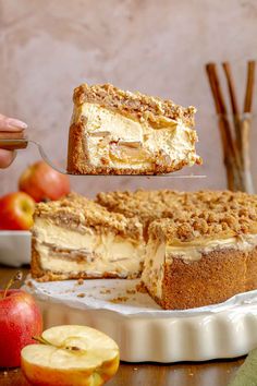 someone is holding a piece of cake with apples in the background and an apple on the side