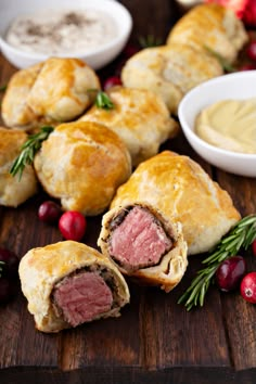 pastrami rolls on a wooden cutting board with cranberries and sauces