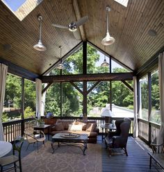 a covered porch with couches, chairs and tables