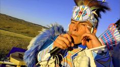 a native american man talking on a cell phone and holding a microphone to his ear