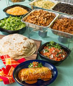 a table topped with lots of different types of food and plates filled with tacos