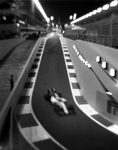 a black and white photo of a race car going down the track at night time