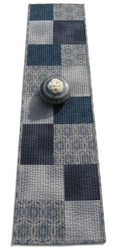 a blue and gray rug with a stone on it