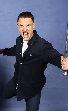 a man holding two swords in one hand and making an angry face with his mouth wide open