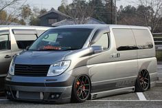 two vans parked in a parking lot next to each other, one is silver and the other is black