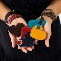 two hands holding small leather heart shaped key fobs in each other's palms