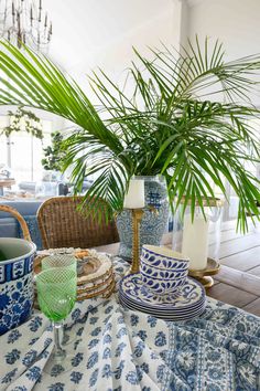 a table with blue and white plates, vases and plants