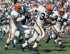 an old photo of football players running on the field