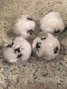 four glass balls decorated with black and white spider webs are sitting on a marble surface