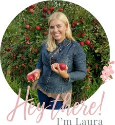 a woman holding two apples in front of an apple tree with the words hey, there i'm laura