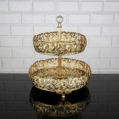 a three - tiered cake stand on a black table with white brick wall in the background