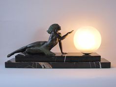 a bronze statue sitting on top of a marble base next to a white light bulb