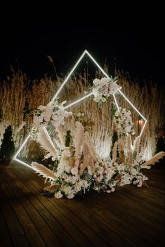 an arrangement of flowers and feathers is lit up at night