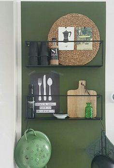 two shelves with utensils and other kitchen items on them in a green room