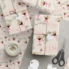 some wrapping paper and scissors are on the table next to it's tags, twine and yarn