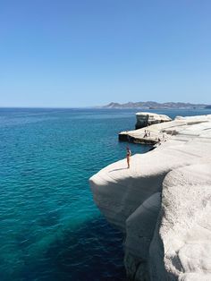 a person standing on the edge of a cliff over water