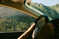 the view from inside a car looking at mountains and trees