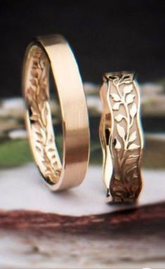 two gold wedding rings sitting on top of each other