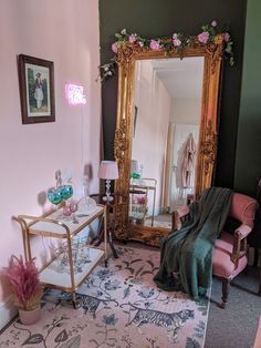 a living room filled with furniture and a large gold framed mirror on the wall next to a pink chair