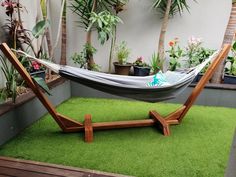 a hammock is set up in the middle of a small garden with potted plants