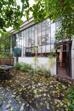 an outdoor patio with lots of leaves on the ground and trees in front of it