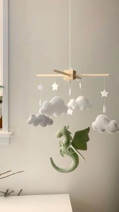 a crib mobile with clouds, stars and a green dragon hanging from the ceiling